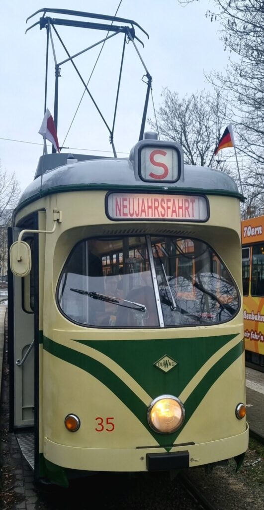 Von vorne, beige mit grünem Streifen und Dreieck, als Linie wird ein "S" gezeigt, als Fahrtziel "NEUJAHRSFAHRT"