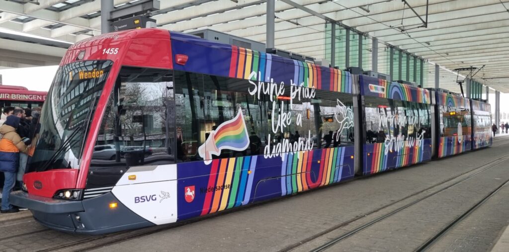 Von schräg vorne rechts, das eigentliche rot-weiß-graue Design wurde überklebt mit dunkelblauer Folie, darüber rote, orangene, gelbe, grüne, blaue und hellblaue Streifen, einem Peace- und einem geflügelten Löwensymbol sowie mehrere Sprüche wie z.B. ''Shine pride like a Diamond''